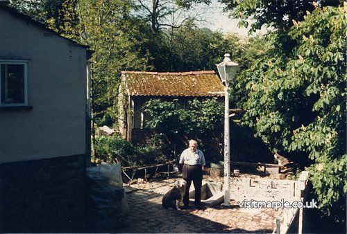 A shot of Reg Walters, then owner of Iron Bridge Cottage, in the garden with his dog as viewed from the Iron Bridge. Taken in late 1980s. 